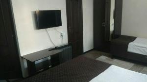 Habitación con cama y TV en la pared. en hotel Tourist, en Karakol