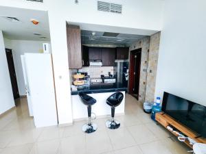 a kitchen with two black bar stools and a television at Comfy Studio with Stunning Vista, Pool and Gym in Abu Dhabi
