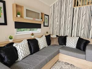 a living room with a gray couch with pillows at Pods 1 and 2 Willow Bank in Market Rasen