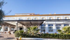 un grande edificio bianco con palme di fronte di Hotel Restaurante Los Molinos a Écija