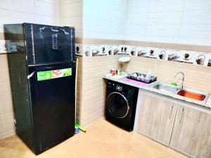 La cuisine est équipée d'un réfrigérateur noir et d'un évier. dans l'établissement Résidence Inaya, à Oran