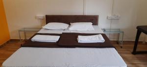 Aaryan Beach Resort في Murūd: سرير كبير عليه طاولتين زجاجيتين