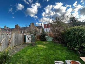a backyard with a fence and a yard with green grass at Waltham Cross Rooms in Cheshunt