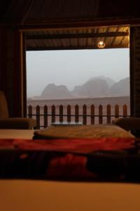 a bedroom with a bed and a large window at Wadi Rum Relaxation Camp in Wadi Rum