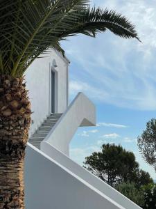 a white house with a staircase next to a palm tree at Hermoso Luxury Suites in Monolithos