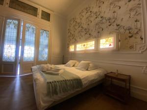 um quarto com uma cama com lençóis brancos e janelas em The Museum - Au Lit, Jérôme! em Antuérpia