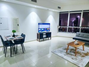 a living room with a tv and a table and chairs at Huge water front 1BR Apt with 2 Sofa Beds+King Bed in Alreem Island in Abu Dhabi