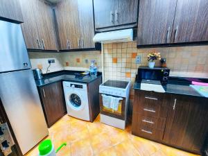 a kitchen with wooden cabinets and a washer and dryer at Huge water front 1BR Apt with 2 Sofa Beds+King Bed in Alreem Island in Abu Dhabi
