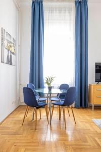 a dining room with a glass table and blue chairs at Super Central Cozy Home on the St. Stephen Road in Budapest