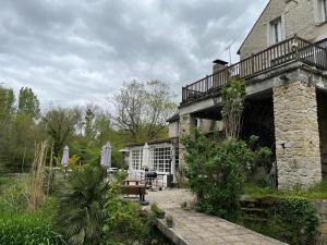 a building with a porch and a table and a bench at Les Amis du Moulin 