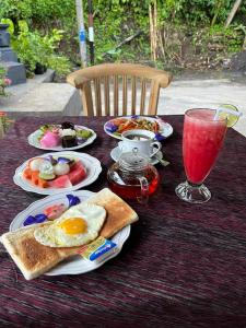 una mesa con platos de desayuno y una bebida en Manuk Dewata Villa, en Sidemen