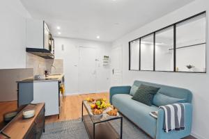 ein Wohnzimmer mit einem blauen Sofa und einem Tisch in der Unterkunft Le Marais - CityApartmentStay in Paris