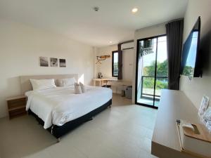 a bedroom with a white bed and a large window at Double J Hotel in Chiang Mai