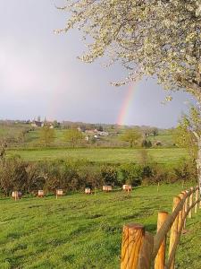um grupo de vacas num campo com um arco-íris no céu em Un chalet suspendu au paradis sur un domaine de 20 hectares em Cressanges