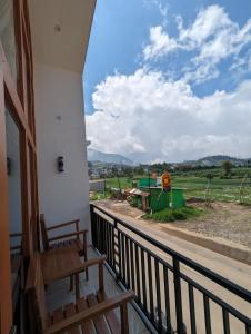 a balcony of a house with a view of a field at Cottage Linggayoni Dieng 1 in Dieng