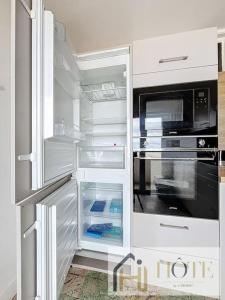 a white refrigerator with an open door with a microwave at Digue de Mer - Appt Vue Mer, 2 Chambres in Bray-Dunes