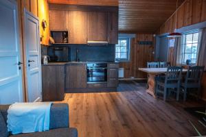 a kitchen with wooden cabinets and a table with chairs at Hytter Dombås in Dombås