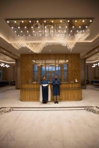 two people standing in a lobby under a chandelier at Hotel Rewa Ladakh in Leh