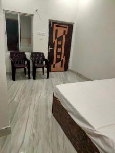 een kamer met 2 stoelen en een bed erin bij Manglam house in Ayodhya