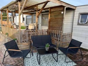 eine Gruppe Stühle und ein Tisch auf einer Terrasse in der Unterkunft Chalet Quattro in bosrijke omgeving in Anloo