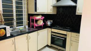イスラマバードにあるSerene Home Apartment (1-Bedroom)のキッチン(白いキャビネット、シンク、コンロ付)