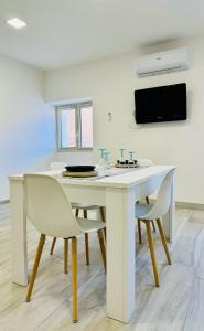 a white dining room table with chairs and a tv at Casa vacanze in centro! in Caltagirone