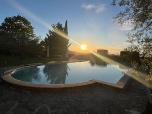 uma piscina com o pôr-do-sol ao fundo em VILLA GIOTTO Florence em Pozzolatico