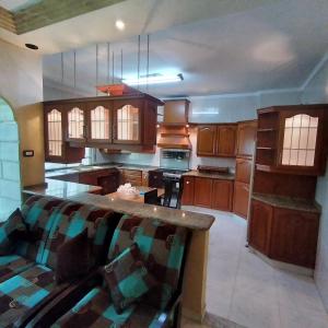 a large kitchen with wooden cabinets and a couch at تلاع العلي دوار الواحه in Rujm ash Sharāʼirah