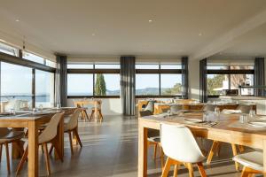 a restaurant with wooden tables and chairs and windows at Victoria Sunset Suites in Port des Torrent