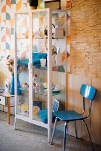 a glass cabinet with dishes and a blue chair at Mon P'tit Hôtel in Le Grau-dʼAgde