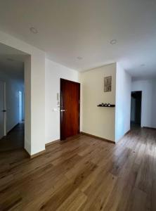 una stanza vuota con pavimenti in legno e una porta di Hab en piso céntrico a 10min del lago a Banyoles