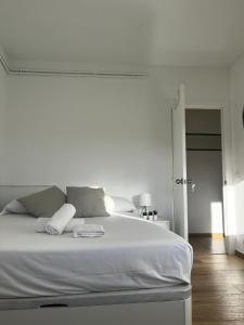 ein weißes Schlafzimmer mit einem großen weißen Bett mit zwei Kissen in der Unterkunft Hab en piso céntrico a 10min del lago in Banyoles