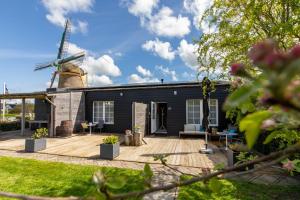 una casa negra con un molino de viento en el fondo en Molenweg 27a, en Zoutelande