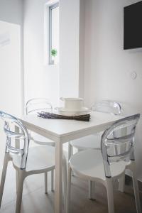 mesa de comedor blanca con 4 sillas y TV en Votsalo Tolo en Tolón