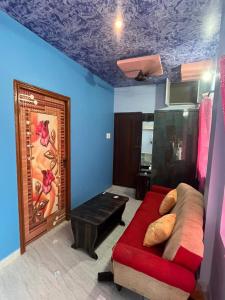 a living room with a red couch and blue walls at PANMOZHI RESIDENCY in Tiruvannāmalai