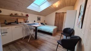 eine Küche und ein Schlafzimmer mit einem Bett und einem Tisch in der Unterkunft Sous le saule in Nods