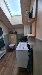 uma casa de banho com um lavatório branco e uma clarabóia em Sous le saule em Nods