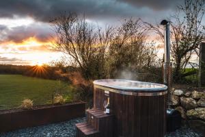 una bañera de hidromasaje en un jardín con puesta de sol en el fondo en Bogee Farm, en Padstow