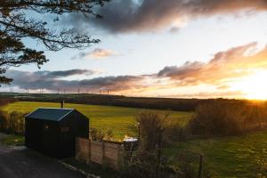 un pequeño cobertizo en un campo con puesta de sol en Bogee Farm, en Padstow