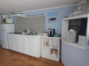 cocina con armarios blancos y nevera blanca en Casa Vacanza Fiori di Maggio, en Pulsano