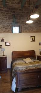 a bedroom with a wooden bed with two tables and two windows at Chambres d'hôte Mas de Bouzou in Grèzes