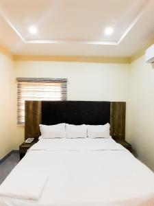 1 dormitorio con 1 cama blanca grande y cabecero negro en Come Inn Hotel, en Rubuchi