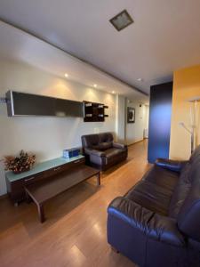 a living room with a leather couch and a table at Pensión Pousada Chiquitin in Melide