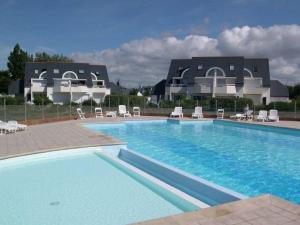 uma grande piscina com cadeiras e um edifício em Appartement Carnac, 3 pièces, 6 personnes - FR-1-477-63 em Carnac