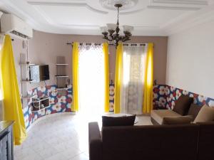 sala de estar con cortinas amarillas y sofá en Hôtel Résidence le diamant, en Kribi