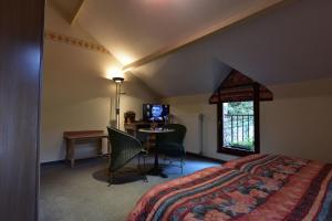 a bedroom with a bed and a table with a television at Hôtel Moulin de la Strument in La-Roche-en-Ardenne