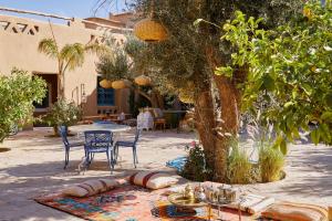 a patio with a table and chairs and a tree at Agafay Desert Hotel in El Karia