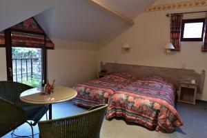 sypialnia z łóżkiem, stołem i krzesłami w obiekcie Hôtel Moulin de la Strument w La-Roche-en-Ardenne