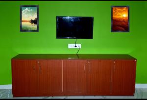 eine grüne Wand mit einem Fernseher auf einem Schrank in der Unterkunft Royal Guest House in Chikmagalur