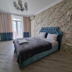 Schlafzimmer mit einem großen Bett mit blauem Kopfteil in der Unterkunft Chisinau Central Apartments in Chişinău